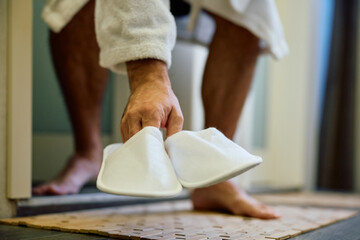 Close up of man using white slippers in bathroom.