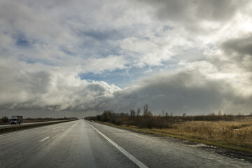A road with a few cars on it and a cloudy sky