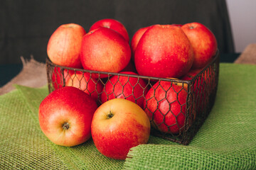 Ripe red apples in a steel basket surrounded by burlap cloth close-up