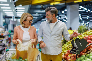 Happy senior couple choosing fruits and vegetables in supermarket