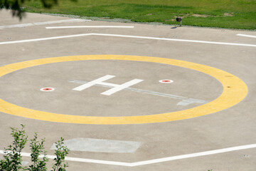 A closeup of an asphalt-covered helipad with a special symbol in the center for helicopter landing.  Helipad in the park.