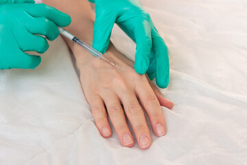 Cosmetologist in green gloves doing mesotherapy, injection of hyaluronic acid into skin of woman's...