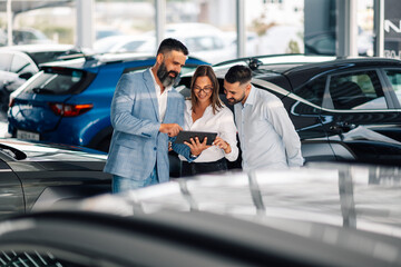 Car dealership discussion with a digital tablet in showroom.