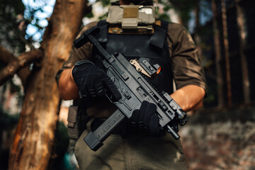 Obraz premium Soldier holding a submachine gun in the forest