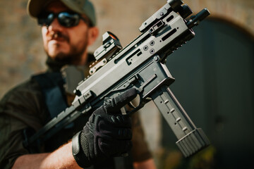 Soldier holding a submachine gun with red dot sight and tactical gloves
