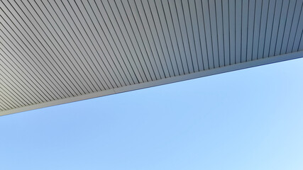 Modern architectural roof design captured against a clear blue sky, emphasizing construction innovation and urban development concepts