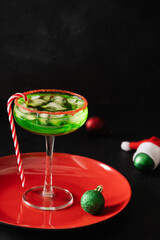 Xmas Green Punch in glass decorated sugar rim on black table make of cool lime sherbet. Tasty drink for Christmas holiday. Rim your festive beverages in red sugar.