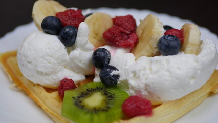 Waffles with whipped cream, blueberries, bananas, raspberries, and kiwi