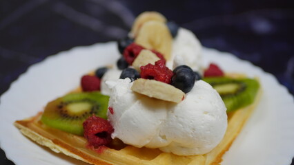 Waffles with whipped cream, blueberries, bananas, raspberries, and kiwi