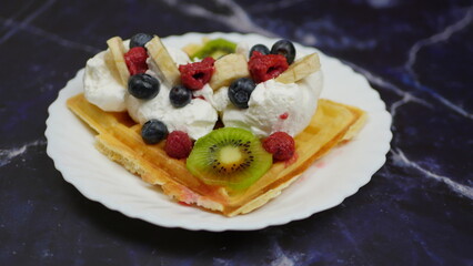 Waffles with whipped cream, blueberries, bananas, raspberries, and kiwi
