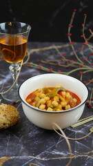 A dish of chickpeas, peppers, carrots and other vegetables with a whole grain roll