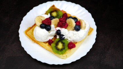 Waffles with whipped cream, blueberries, bananas, raspberries, and kiwi