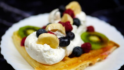 Waffles with whipped cream, blueberries, bananas, raspberries, and kiwi