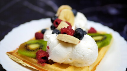 Waffles with whipped cream, blueberries, bananas, raspberries, and kiwi