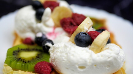 Waffles with whipped cream, blueberries, bananas, raspberries, and kiwi