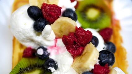 Waffles with whipped cream, blueberries, bananas, raspberries, and kiwi