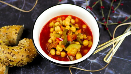 Dish with chickpeas, peppers, carrots and other vegetables with a whole grain roll and a glass of wine
