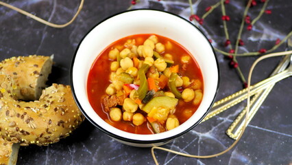 Dish with chickpeas, peppers, carrots and other vegetables with a whole grain roll and a glass of wine

