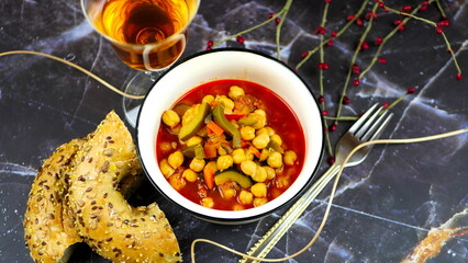 Dish with chickpeas, peppers, carrots and other vegetables with a whole grain roll and a glass of wine
