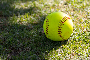 girls yellow softball sitting on grass