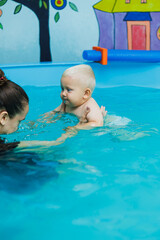 The boy has been swimming with a coach in the pool for one year. Teaching a child to swim. Swimming pool for children.
