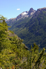 Beautiful close up of snowy rocky mountains and forest with green trees part of a challenging trekking trail that connects Natacion Lake and Cajon del Azul landmarks in El Bolson, Rio Negro, Argentina