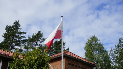 Polish flag on the background of clouds and buildings
