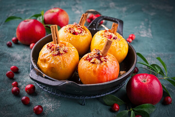 Traditional butter baked cinnamon apples stuffed with marzipan, nuts and cranberries served as close-up in a backing pot