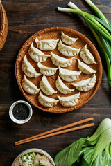 gyoza making, asian dumplings with meat and cabbage, steamed, on a bamboo base in the hands of a female cook