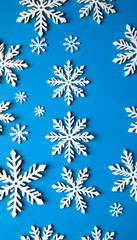 Fototapeta premium White wooden snowflakes on blue background. Christmas, New Year, winter holidays pattern, detailed