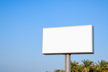 a large billboard with the sky in the background and palm trees below