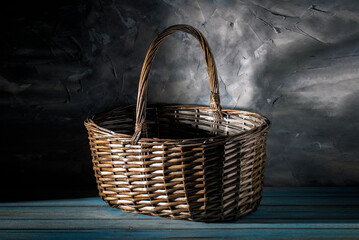 Wicker basket on blue wooden table against grey wall