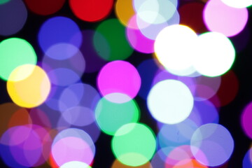 Una toma de cerca de una fondo abstracto de luces de navidad de diferentes colores en la oscuridad. Desenfoque bokeh