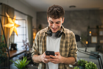 Portrait of man blogger stand at home studio and use mobile phone