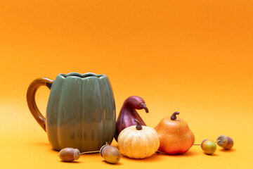 Still life with pumpkins, apples, acorns and jug on orange background