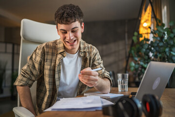 Focused young adult man write notes in notebook prepare for exam