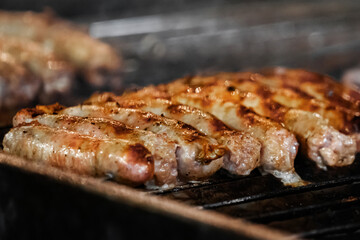 Close-up of grilled sausages sizzling on barbecue showcasing the charred and golden texture of the meat as it cooks over the fire