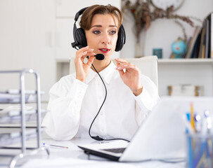 Happy call center operator talking with client and smiling