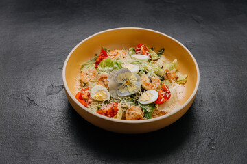 Shrimp Caesar salad with boiled egg, cherry tomatoes, parmesan, and edible flower garnish