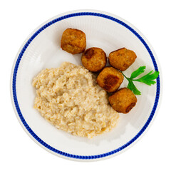 On checkered tablecloth there is white round plate with meatballs albondigas, garnished with porridge oatmeal. Traditional Spanish appetizer and hearty dish, served with or without side dish. Isolated