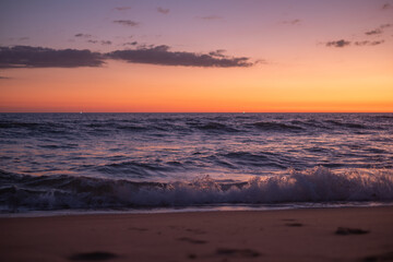 Obraz premium A serene sunset over the calm ocean waves at a peaceful beach, capturing the vibrant colors of dusk