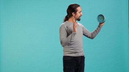 Impatient man looks at clock, waiting for time to pass, excited to be done with tasks, isolated...