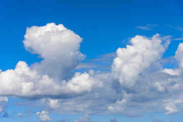 Unique aerial view of bodies of cumulus clear white clouds towers in bright blue sky background.