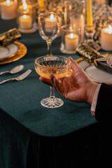Hand holding a wine glass on New Year's party night. Christmas decor in a Holiday cozy dinner
