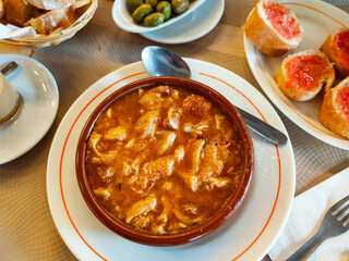 Beef stomach stew, potatoes, seasonings, tomato sauce. Traditional dish of Russian cuisine prepared in national restaurant for guests of institution, served in clay tureen with slices of bran bread