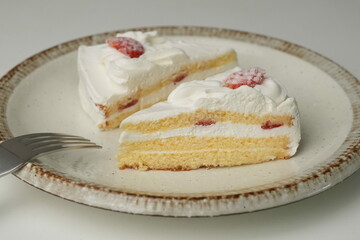 Two Japanese strawberry shortcakes and a large fork on a stylish large plate on a white table