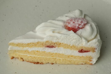 One small Japanese strawberry shortcake on a stylish large plate on a white table