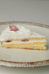 One small Japanese strawberry shortcake on a stylish large plate on a white table