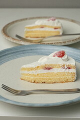 Japanese strawberry shortcake and fork on each stylish large and small plate on a white table