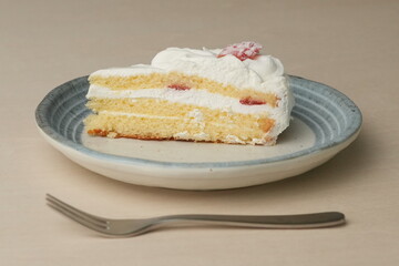 Japanese strawberry shortcake and fork on each stylish large and small plate on a wooden table
